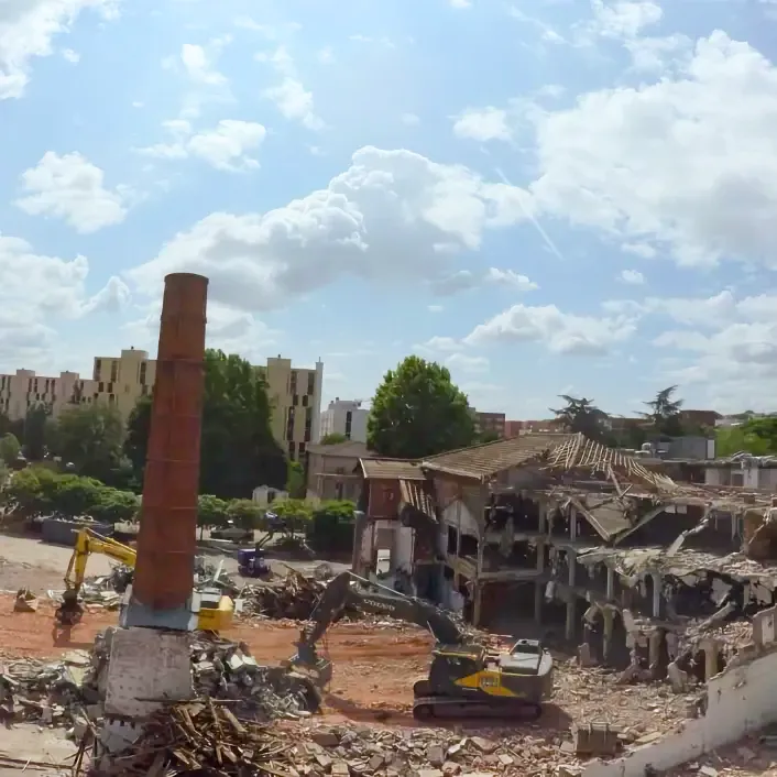 Timelapse de suivi de chantier : zone de démolition avec pelleteuses et cheminée en brique